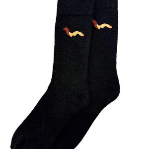 May include: A pair of black socks with a brown and yellow dachshund design near the cuff. The socks are made of a soft material and are suitable for everyday wear. The socks are a fun and unique accessory.