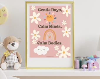 May include: A framed wall art print with a dusty pink background featuring white daisy illustrations, a smiling sun, a rainbow, and a white cloud. The text reads: Gentle Days, Calm Minds, Calm Bodies. The frame is gold-colored and rectangular.
