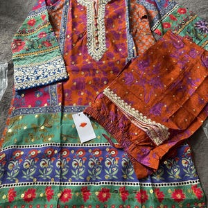 May include: A multi-colored, floral print, long-sleeved top and pants set. The top has a V-neckline and a button closure. The pants have an elastic waistband. The fabric is a cotton blend.