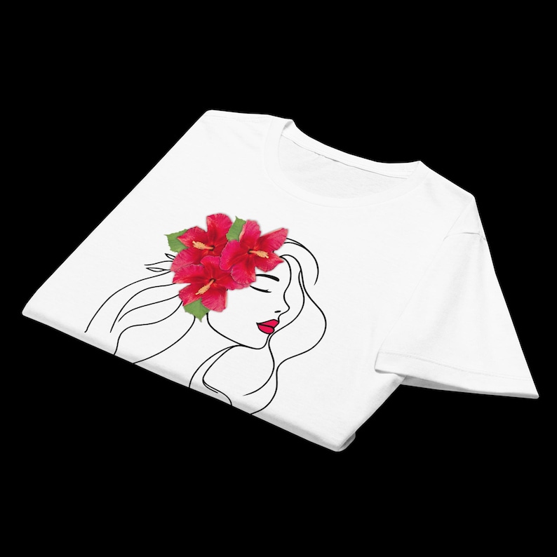 Puede incluir: Camiseta blanca con un dibujo lineal minimalista del perfil de una mujer con pelo largo y labios rojos. Un grupo de flores de hibisco rojas adorna su cabello. El dise&ntilde;o est&aacute; centrado en la parte delantera de la camiseta.