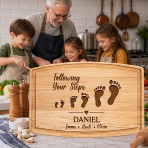 May include: A rectangular wooden cutting board featuring the engraved text Following Your Steps, a series of four pairs of footprints in increasing sizes, a small heart icon, the name DANIEL, and the names Emma, Noah, and Olivia below.