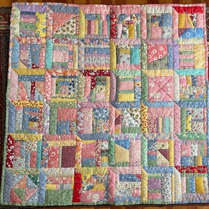 May include: A patchwork quilt with a variety of floral and geometric patterns in pastel colors. The quilt features squares and rectangles of fabric in shades of pink, blue, yellow, and green, creating a cozy and colorful design.
