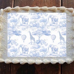 May include: A rectangular cake with white frosting and a blue and white safari-themed design. The design features elephants, giraffes, hot air balloons, and trees. The cake is decorated with a white frosting border.