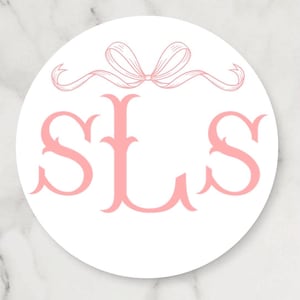 May include: A round white sticker with a pink monogram design. The monogram features the letters "SLS" in a decorative font, topped with a pink ribbon bow. The sticker has a marble-like background.