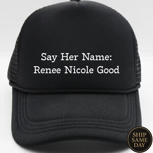 May include: Black trucker hat with the text "Say Her Name: Renee Nicole Good" in white. The hat has a mesh back and a curved brim. A round sticker on the bottom right corner says "Ship Same Day".