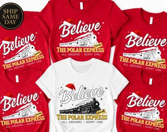 May include: Red and white t-shirts with a Christmas-themed graphic. The design includes the word "Believe" above a train illustration, a Santa hat, and the text "The Polar Express, All Aboard, Admit One".