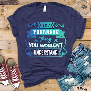 Puede incluir: Camiseta azul marino con un gráfico turquesa y azul que dice "It's a YOURNAME thing you wouldn't understand." La camiseta se combina con pantalones cortos de mezclilla y zapatillas rojas.