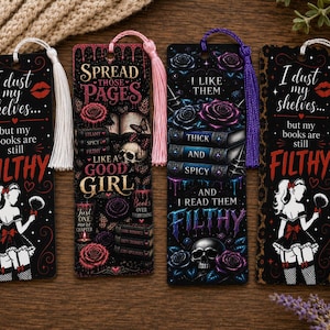 May include: Four rectangular bookmarks with tassels. Two feature a maid illustration and the text I dust my shelves but my books are still FILTHY. One says SPREAD THOSE PAGES LIKE A GOOD GIRL with a skull. One says I LIKE THEM THICK AND SPICY.