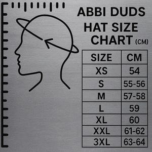 May include: A silver hat size chart from Abbi Duds. The chart includes a diagram of a head with a measuring line, and a table with sizes XS to 3XL, corresponding to head circumferences from 54 cm to 64 cm.