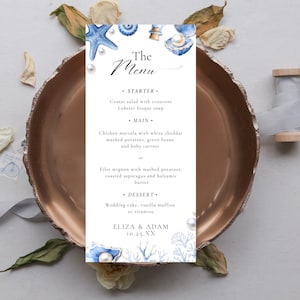 May include: A wedding menu card with a nautical theme. The menu features blue watercolor illustrations of seashells, starfish, and pearls. The menu includes the text "The Menu", starter, main, and dessert options. The names Eliza & Adam and the date 10.25.XX are also included.