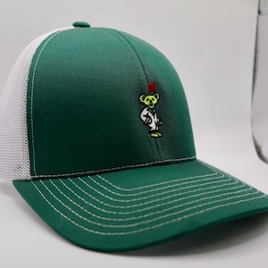May include: A green baseball cap with a white mesh back and a curved brim. The cap features a stitched design and an embroidered cartoon bear wearing a fez. The hat is a classic style.