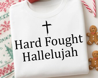 May include: White sweatshirt with a black cross graphic and the words "Hard Fought Hallelujah." The image includes a wrapped gift, candy canes, and gingerbread men, suggesting a holiday theme.