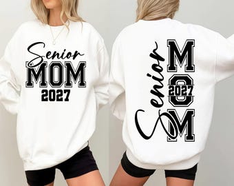 Puede incluir: Una sudadera blanca de manga larga con texto en negro. El frente muestra 'Senior MOM 2027' en una mezcla de letra cursiva y de molde. La parte posterior presenta la palabra 'Senior' en cursiva, con 'MOM' en letras de molde y '2027' centrado.