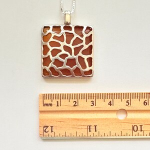 Handgemaakte hanger van sterling zilver met oranje vierkant geslepen onyx en dierenpatroon.