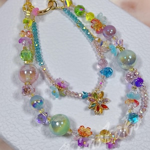 Correa de cuentas para teléfono: dije de flores giratorias kawaii, accesorio artesanal de estilo Fairycore para teléfonos, llaves y billeteras. Elegante y moderno.