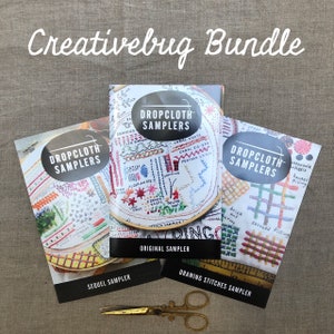 May include: A bundle of embroidery samplers with the text "Creativebug Bundle". The samplers include "Original Sampler", "Sequel Sampler", and "Drawing Stitches Sampler". Gold scissors are at the bottom.