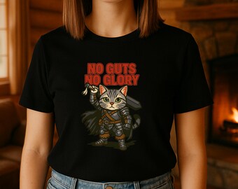 May include: Black t-shirt featuring a cartoon cat warrior with a sword and armor, with the text "NO GUTS NO GLORY" in red. The cat has gray and black stripes and green eyes. The shirt is made of a soft material.