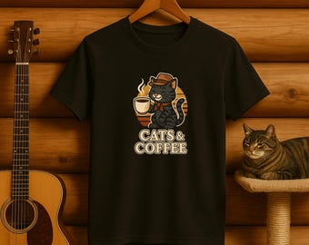 May include: Black t-shirt featuring a cartoon cat wearing a hat and scarf, holding a coffee cup. The design includes the text "CATS & COFFEE" in a retro style, set against a circular background with a sunset design.