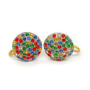 May include: A pair of round stud earrings. Each earring is covered in a mosaic of colourful rhinestones in red, blue, green, yellow, and clear. The earrings have a gold-coloured loop for the ear.