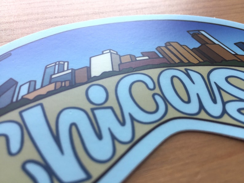 Op de afbeelding: Een blauwe en witte sticker met een gestileerde skyline en het woord "Chicago" in een blauw lettertype.