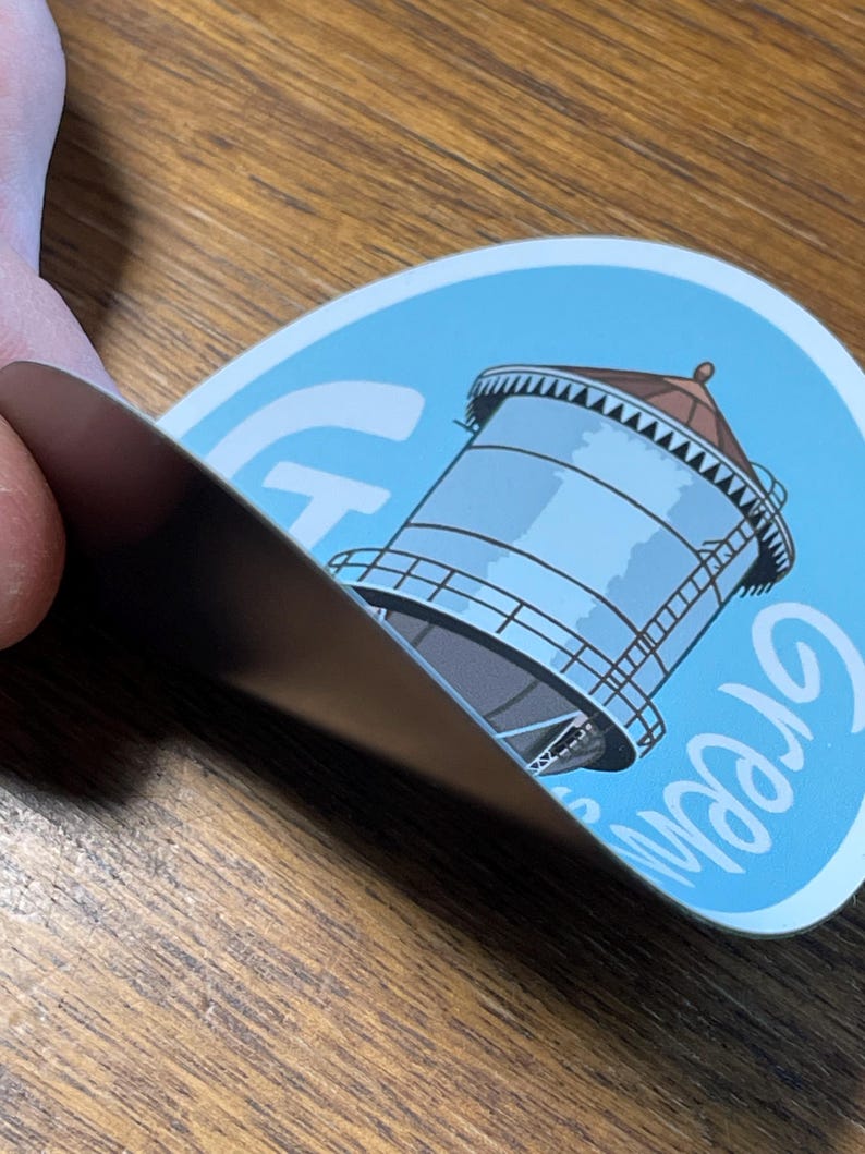 May include: A blue and white round sticker featuring a water tower illustration and the word "Crown" written in white cursive.