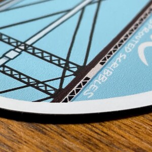 May include: A blue and white round sticker with a black and white illustration of a bridge. The sticker has the text "Spotted Squirrel" written on it.