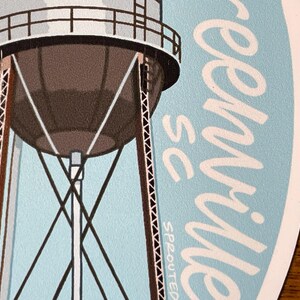May include: A blue and white sticker featuring a water tower and the text "Greenville, SC" in white cursive writing.