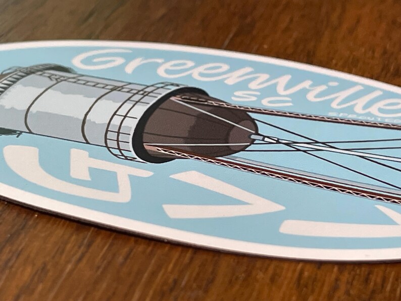May include: A blue and white oval sticker with a drawing of a water tower and the text "Greenville SC" in a white cursive font.