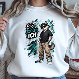 Könnte beinhalten: Weißes Sweatshirt mit einem Cartoon-Wolf, der eine Sonnenbrille, ein schwarzes T-Shirt und eine beige Hose trägt. Der Wolf steht vor türkisfarbenen und schwarzen Farbspritzern. Der Text auf dem Sweatshirt lautet "Cool, cooler, ICH."