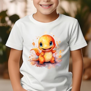 Puede incluir: Camiseta blanca con una ilustración de acuarela de un personaje Charmander. La criatura naranja y amarilla tiene una expresión amigable y está rodeada de salpicaduras coloridas. La camiseta es una prenda infantil.