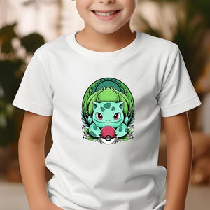 May include: White t-shirt with a Bulbasaur graphic. The design shows a green Bulbasaur holding a red and white Poké Ball, set against a green and white background. The t-shirt has a classic crew neck style.