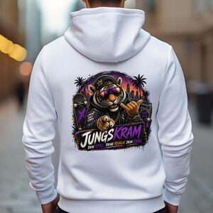 Könnte beinhalten: Weißer Kapuzenpullover mit einem Grafikdruck auf dem Rücken. Die Grafik zeigt einen Tiger mit Sonnenbrille und Kappe, der den Daumen hochhält. Der Aufdruck enthält den Text "JUNGS KRAM" in einer stilisierten Schriftart.