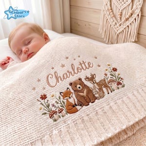 Pu&ograve; includere: Una coperta per neonati in maglia color crema con un ricamo raffigurante una volpe, un orso, un cervo e un coniglio circondati da funghi e fiori. Il nome Charlotte &egrave; ricamato in corsivo marrone sopra gli animali con piccole stelle.