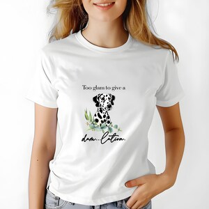 May include: White t-shirt featuring a Dalmatian dog illustration with black spots and the text "Too glam to give a dam...ation." The graphic includes green foliage. The shirt is a casual wear item.