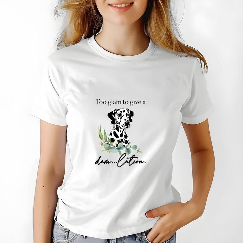May include: White t-shirt featuring a Dalmatian dog illustration with black spots and the text "Too glam to give a dam...ation." The graphic includes green foliage. The shirt is a casual wear item.