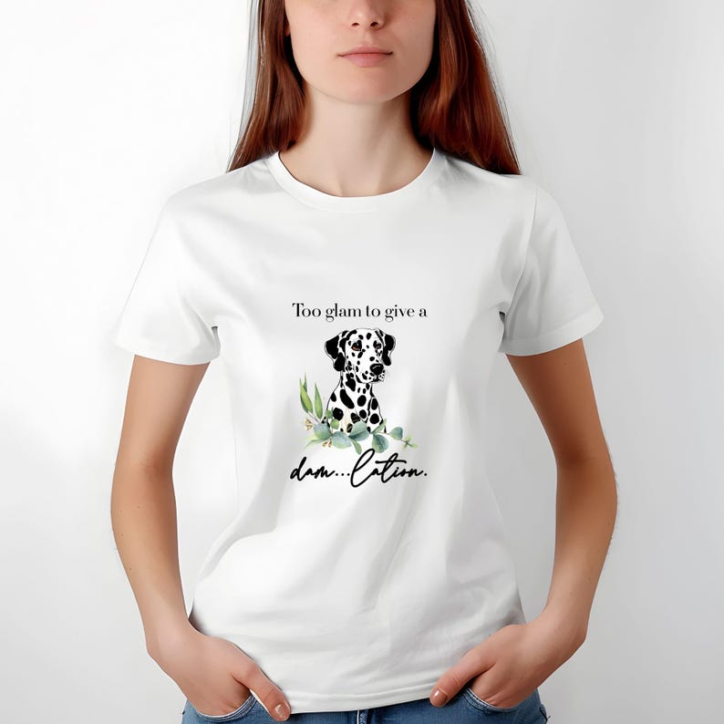 May include: White t-shirt featuring a Dalmatian dog illustration with black spots and green leaves. The text on the shirt reads "Too glam to give a damn...lation."
