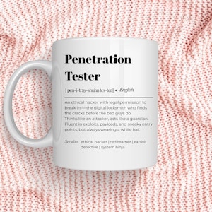 Puede incluir: Taza de cerámica blanca con el texto "Penetration Tester" en negro. La taza incluye una definición del término, que describe a un hacker ético. La taza está sobre un fondo de punto rosa.