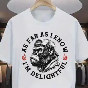 May include: White t-shirt featuring a black and white illustration of a gorilla wearing a baseball cap. The text around the gorilla reads "AS FAR AS I KNOW I'M DELIGHTFUL" in a circular design with red flame accents.