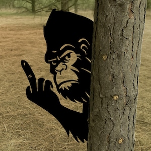 May include: A black silhouette of a gorilla peeking out from behind a tree trunk. The gorilla is making a rude gesture with its middle finger.