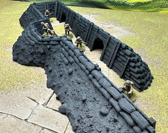 May include: A detailed miniature war game terrain piece depicting a trench system. The dark gray trench is made of stacked sandbags and wooden supports. Small soldier figurines are positioned within the trench, suggesting a battle scene.
