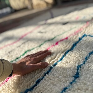Ivory hand knotted wool rug with colorful geometric motifs and natural fringe