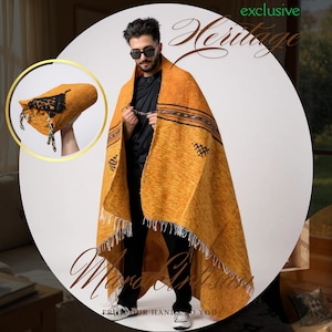 May include: Mustard yellow shawl with black geometric patterns and fringe. The shawl is draped over a person wearing black clothing and sunglasses. A smaller image shows a matching hat. The text "exclusive Heritage" and "Mana Artisans" is visible.
