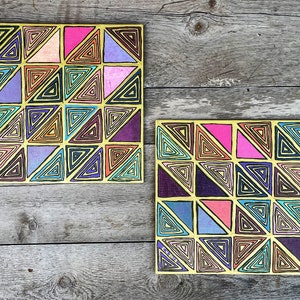 May include: Two yellow squares with a geometric pattern of overlapping triangles in various colors, including pink, purple, blue, and orange. The triangles are outlined in black and have a swirling pattern inside.