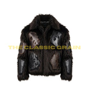 Op de afbeelding: Een donkerbruine imitatiebontjas met leren patches. De jas heeft een brede kraag en een getextureerde uitstraling. De tekst "THE CLASSIC GRAIN" staat onderaan de jas.