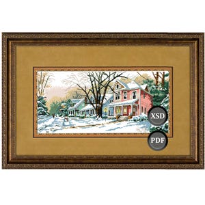 Puede incluir: Punto de cruz enmarcado de una escena de pueblo invernal. La obra representa casas cubiertas de nieve en tonos verdes y rojos, con árboles sin hojas y un camino nevado. El marco es dorado oscuro y ornamentado.
