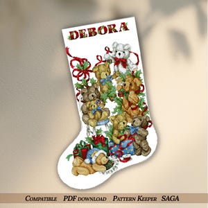 May include: A white Christmas stocking featuring a collection of teddy bears, holly, and wrapped gifts. The name "DEBORA" is embroidered at the top in red and green. The stocking is decorated with red ribbons and bows, creating a festive holiday theme.
