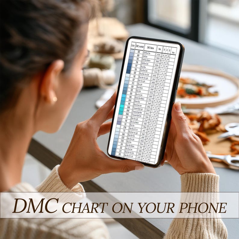 May include: A person holding a smartphone displaying a DMC color chart. The chart features rows of color swatches and corresponding DMC numbers. The phone screen is filled with text, and the image is set against a blurred background.