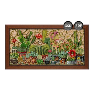 Puede incluir: Un bordado a punto de cruz enmarcado con una variedad de cactus y suculentas en macetas. La obra de arte muestra una diversa colección de cactus verdes con flores rojas y rosas, sobre un fondo de pared de piedra. El marco es de color marrón oscuro.