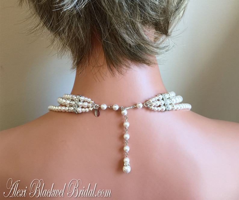 May include: A multi-strand pearl necklace with a silver clasp and a single strand of pearls extending from the back. The necklace is white and has a delicate, feminine look.