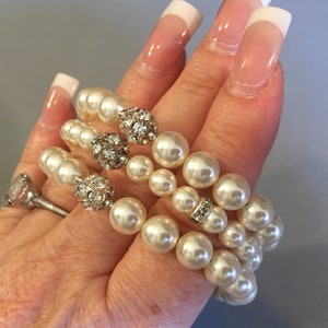 pearl bracelet with rhinestone accents. The bracelet has 3 strands pearls stacked on top of each other and are a cream color.